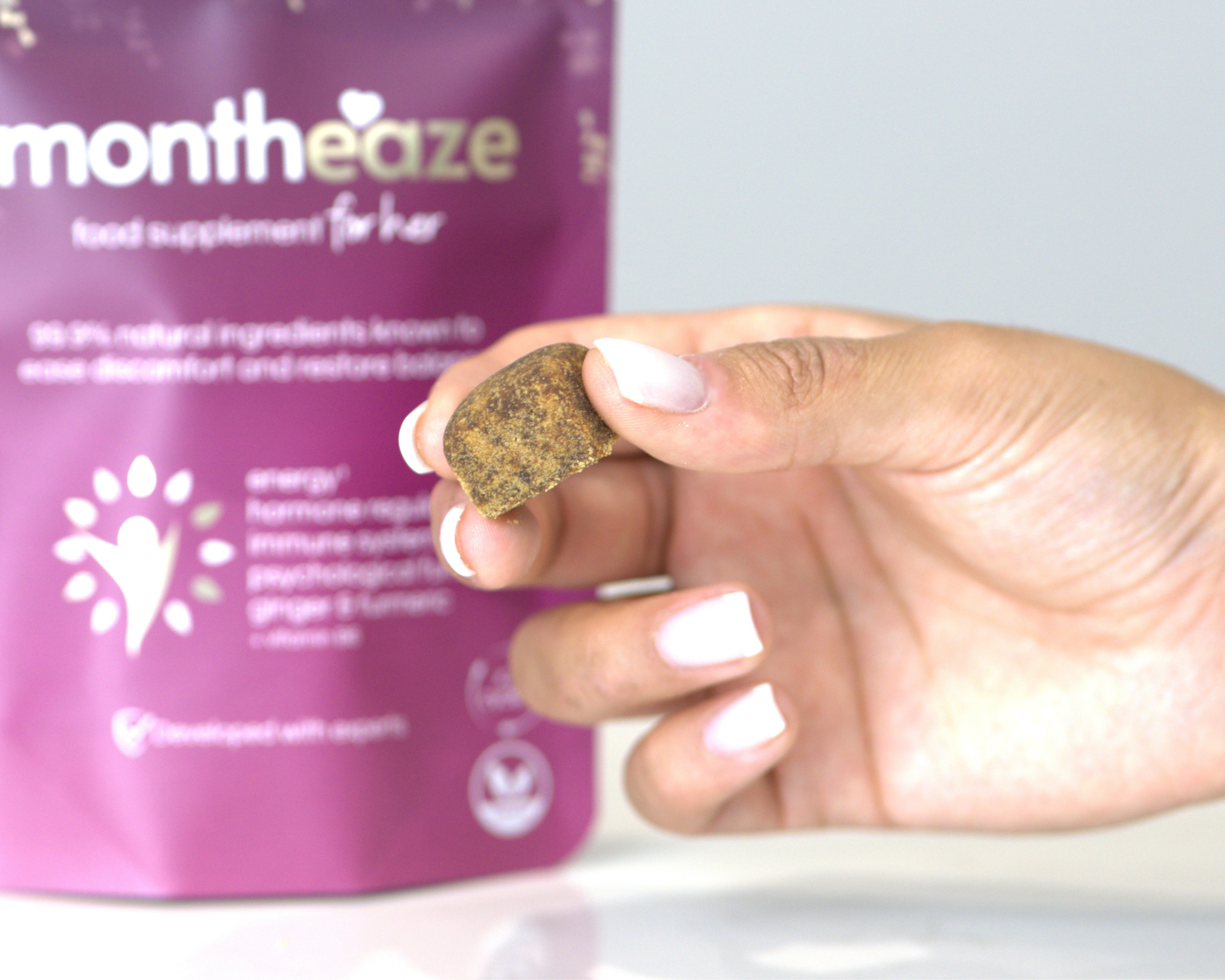 Hand holding a montheaze cube in front of a Montheaze food supplement package.