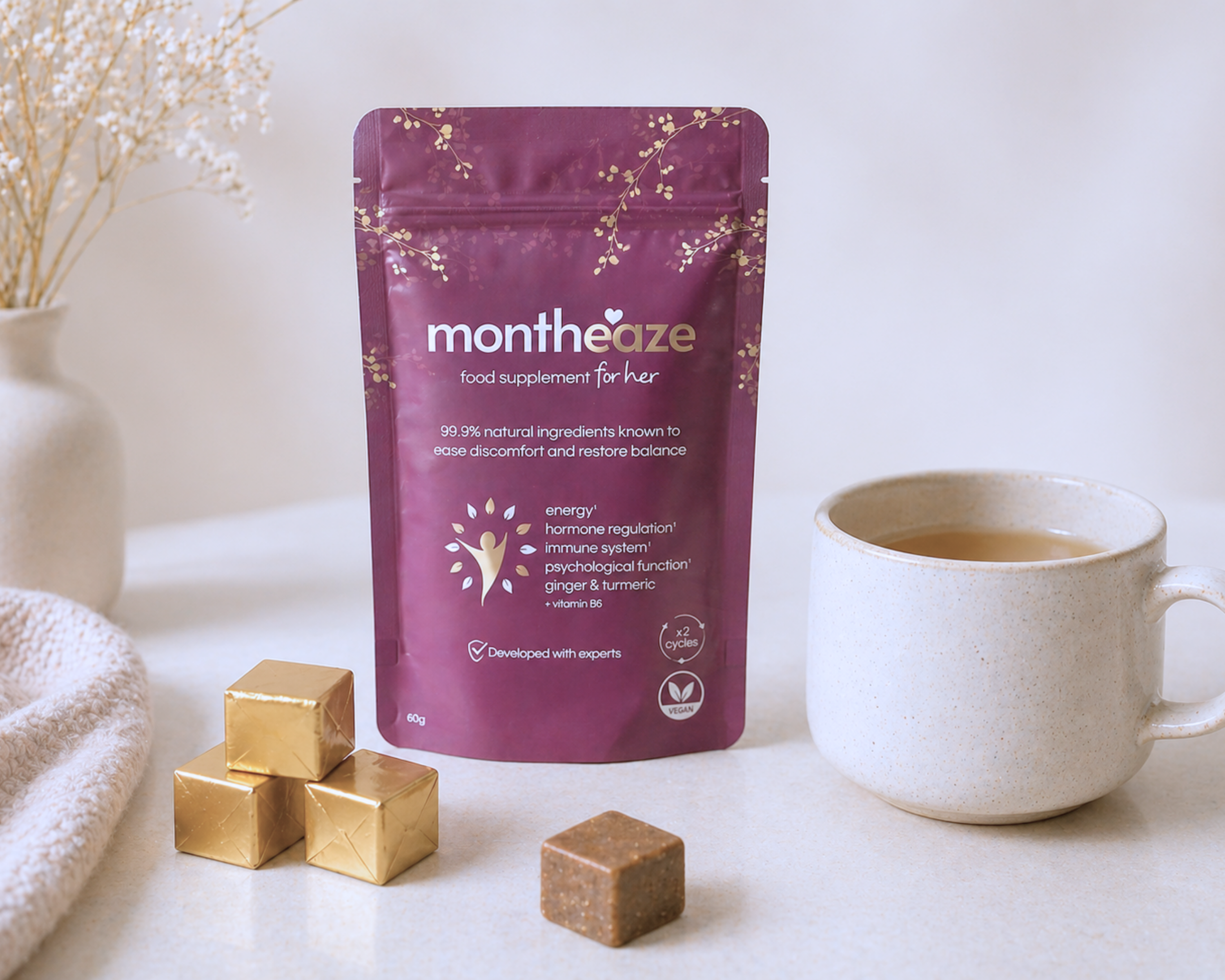 Purple package of 'montheaze' on a white surface with a cup and cubes.